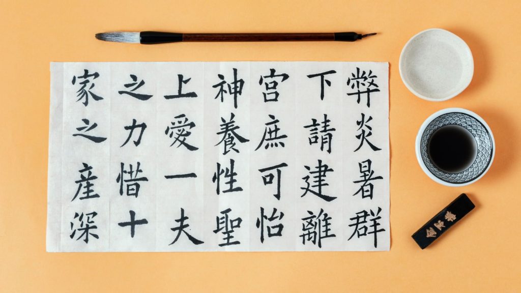 Θεματική εικόνα για "κινεζικά γράμματα, τι σημαίνουν". Χαρτί με κινεζικούς χαρακτήρες. Απεικονίζεται πινέλο & δοχείο μελανιού.